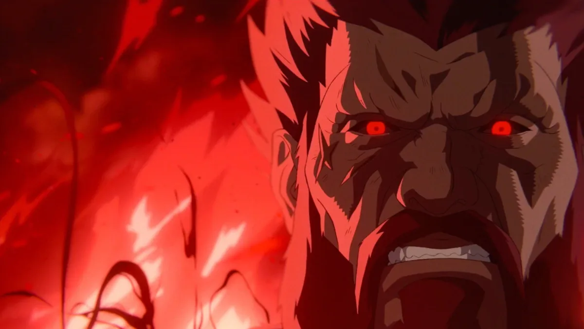 An intense, close-up shot captures the furious visage of the demon martial artist Akuma from a hand-drawn 2D animated flashback sequence in the upcoming Street Fighter (2026) film. His face dominates the right side of the frame, showing a tightly gritted jaw, bared teeth, and prominent facial wrinkles that emphasize his sheer rage. His eyes burn a fierce, glowing solid red, lacking pupils and channeling his mastery of the dark Satsui no Hado energy. He features dark, spiky hair and a thick beard surrounding his mouth. The entire background on the left is engulfed in a chaotic, fiery red and black aura with swirling energy tendrils, underscoring the destructive and ominous atmosphere that follows his presence.