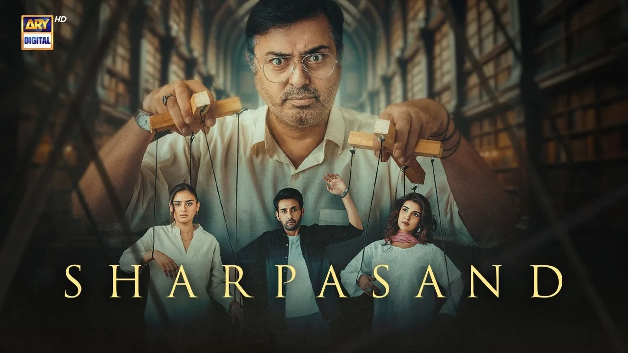 A promotional poster for the Pakistani television drama Sharpasand, broadcasted on ARY Digital. The imagery features a large, dominant figure of actor Nauman Ijaz in the background, wearing glasses and holding wooden puppet bars with strings attached to the characters below. In the foreground, three actors—Iqra Aziz, Bilal Abbas Khan, and another female lead—stand suspended like marionettes against a backdrop of an expansive, multi-tiered classical library filled with books. The overall color palette is muted and dramatic, emphasizing themes of control, manipulation, and mystery.