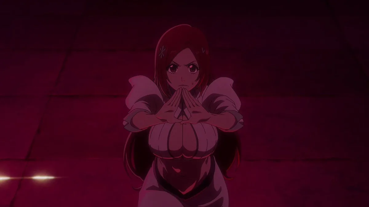 A low-light, red-tinted anime screenshot of Orihime Inoue from Bleach: Thousand-Year Blood War, shown from the waist up as she stands defensively on a dark stone floor, bringing her hands together in front of her chest to activate her Shun Shun Rikka barrier technique while looking ahead with a focused and determined expression.