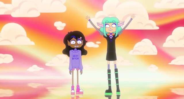 An animation cel from the queer sci-fi comedy Lesbian Space Princess, featuring two characters standing side-by-side against a vibrant, stylized background of soft pastel clouds tinted with a bright pink, orange, and yellow gradient. On the left, Saira stands stiffly with an anxious, wide-eyed expression and clenched teeth, sporting messy dark hair with a blue-and-yellow streak and a lavender turtleneck sweater that reads "SEXY BITCH". To her right, Willow enthusiastically celebrates with her arms raised high in a "V" shape, smiling widely with large round glasses, bright green shoulder-length hair, elongated lavender alien ears with piercings, a short black dress over a purple lace-up shirt, and tall black platform boots accented with lime green strips.