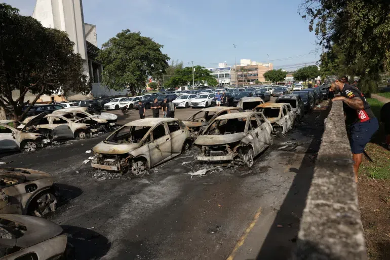 The fatal incident occurred around 9:00 AM local time in the coastal neighborhood of Recreio dos Bandeirantes, located west of downtown Rio de Janeiro.The Collision: Two helicopters collided mid-air during flight. Preliminary reports suggest the aircraft were a Bell 206 and an AS350.The Impact Site: After hitting each other, the aircraft plummeted into the outdoor parking lot of an electric vehicle dealership. The impact ignited a massive blaze that consumed approximately 20 parked vehicles. The fire department deployed around 45 firefighters to control the intense fire, which was complicated by the lithium-ion batteries in the electric cars.
