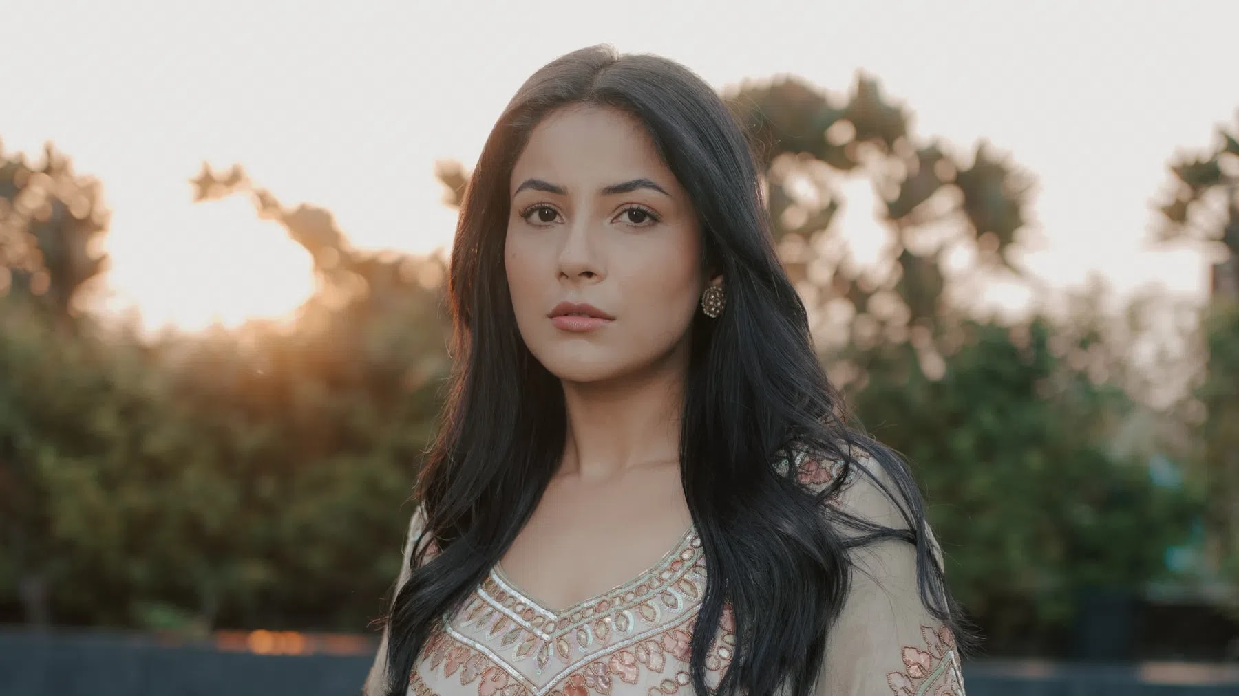 Shehnaaz Kaur Gill is a highly popular Indian actress, model, and singer who became a nationwide sensation after participating in the reality television show Bigg Boss 13 in 2019. Born on January 27, 1993 or 1994, in Punjab, India, she graduated with a commerce degree from Lovely Professional University before pursuing her childhood dream of entering the entertainment industry.She began her career as a model in 2015, debuting in the hit Punjabi music video "Shiv Di Kitaab", followed by an acting debut in the 2017 Punjabi film Sat Shri Akaal England. However, her stint on Bigg Boss 13, where she finished as the second runner-up, completely transformed her career. Audiences fell in love with her bubbly, unfiltered, and deeply expressive personality—affectionately dubbed the "Katrina Kaif of Punjab". Her close bond and chemistry with the late co-contestant Sidharth Shukla also became a massive cultural phenomenon known to fans as "SidNaaz".Following her reality TV breakthrough, Shehnaaz seamlessly transitioned into a mainstream star across both regional cinema and Bollywood. She delivered stellar performances in major Punjabi movies like Honsla Rakh, Kala Shah Kala, and Ranna Ch Dhanna, and later made her official Bollywood debut in Salman Khan's Kisi Ka Bhai Kisi Ki Jaan followed by the comedy-drama Thank You For Coming. Constantly evolving her craft, Shehnaaz has expanded her professional horizons to work behind the camera, marking her debut as a film producer with the Punjabi feature Ikk Kudi. Currently, she continues to capture audiences with high-profile projects, including her leading role in the romance drama Ishqnama.