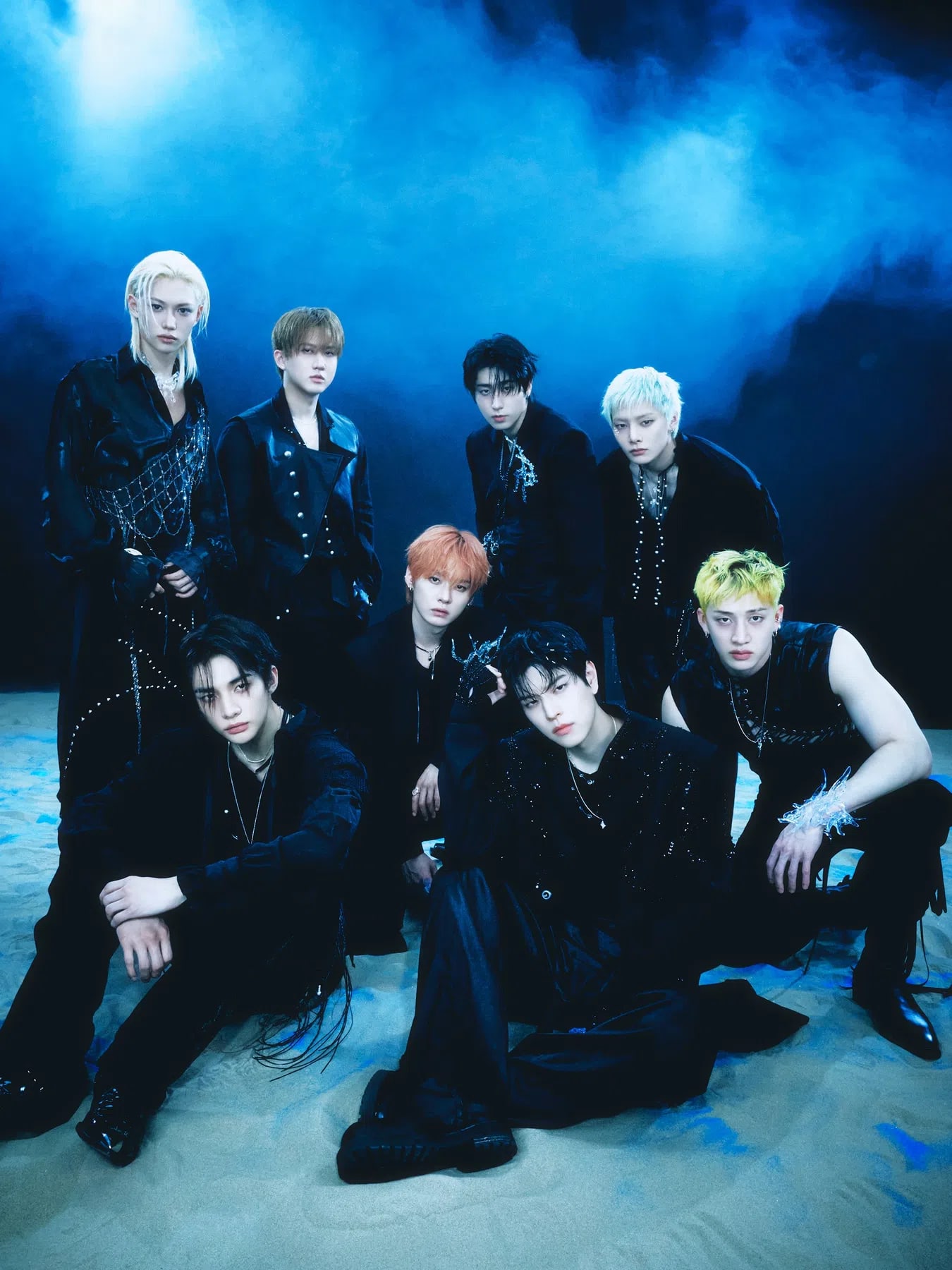 Stray Kids are pictured in a deep, underwater-inspired conceptual group portrait for their JAPAN 4th Mini Album『SUIATSU』, capturing a mysterious, siren-like aesthetic ahead of its official release on November 25, 2026. Dressed in highly structured dark outfits embellished with metallic hardware, shimmering chains, and draped pearl networks, the eight members—Bang Chan, Lee Know, Changbin, Hyunjin, Han, Felix, Seungmin, and I.N—pose submerged against a dark blue marine backdrop filled with floating bubbles. Above the group, the album's title SUIATSU (meaning water pressure) is rendered in a distorted, liquid chrome typeface that flows across the top of the jacket image.