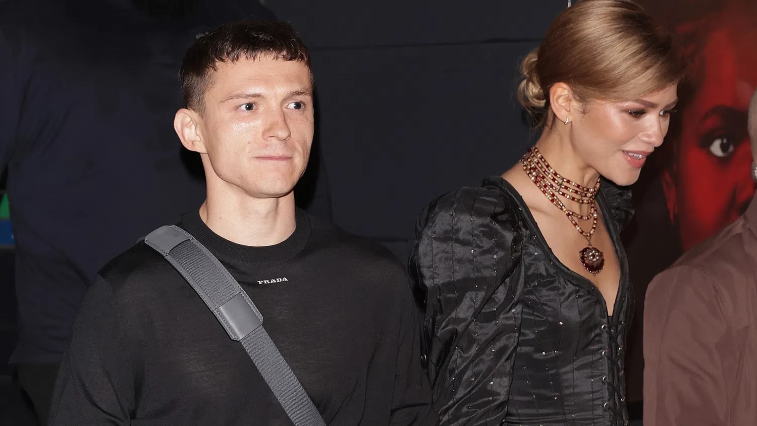 Tom Holland is pictured wearing a sleek black Prada long-sleeved shirt with a subtle embroidered logo on the chest.Zendaya is shown in a structured, black Elizabethan-inspired corset dress featuring intricate detailing.The photo was captured in London while the pair were leaving a press night performance for Holland's role in Romeo and Juliet.Zendaya accessorized the outfit with several layered, beaded necklaces featuring a central jeweled pendant.
