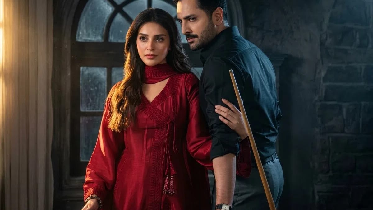 This cinematic promotional still features Pakistani actors Anmol Baloch and Danish Taimoor in a moody, dimly lit room, posing next to a green snooker table under a large, arched multi-pane window that filters in soft exterior light. On the left, Anmol Baloch stands facing forward with a serious, wide-eyed expression, dressed in an elegant deep red silk anarkali-style tunic featuring intricate embroidered borders, an asymmetric front tie closure with tassels, and a matching red dupatta draped around her neck. Her long, dark wavy hair falls over her shoulders, and her right hand rests lightly on the edge of the snooker table near a single red ball. Stepping out from behind her on the right is Danish Taimoor, clad in a sleek, buttoned-down black dress shirt and dark trousers, sporting a neat mustache and stylized side-parted hair. He looks intently off-camera with a stern, focused gaze while leaning forward, his left hand grasping a wooden cue stick that rests diagonally against the table and his right arm partially hidden as she rests her hand upon his forearm. The atmospheric background is defined by dark, rough-textured stone brick walls, a beige curtain draped to the far left, and a subtle golden glow casting highlights along the contours of their faces and outfits, creating a tense, dramatic narrative ambiance suitable for a television drama poster.