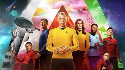 A promotional group poster features nine cast members from the sci-fi series Star Trek: Strange New Worlds arranged against a vibrant backdrop of geometric color segments showcasing different alien planets, space vistas, and nebula skies. In the center stands Captain Christopher Pike, a silver-haired man in a bright yellow Starfleet uniform with his hands clasped together, flanked closely by Spock in a blue uniform on his left and Number One (Una Chin-Riley) in a yellow uniform on his right. Other crew members—including Nyota Uhura, Nurse Christine Chapel, Dr. M'Benga, Erica Ortegas, La'an Noonien-Singh, and another crewmate—are distributed symmetrically around them, wearing their respective red, blue, or yellow uniforms and striking serious, looking-forward poses.