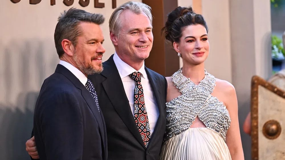 Matt Damon, director Christopher Nolan, and Anne Hathaway command the red carpet at the star-studded world premiere of The Odyssey on Tuesday, July 14, 2026, at the AMC Lincoln Square theater in New York City. Standing together from left to right, the powerhouse trio celebrates the release of their highly anticipated epic fantasy blockbuster, marking a major cinematic reunion over a decade after they first collaborated on 2014's Interstellar. Positioned in the center, Nolan guides his leading actors through a wave of flashing cameras and cheering fans, just days ahead of the film's global theatrical rollout. The high-profile event draws massive media attention to Manhattan's Upper West Side, anchoring the promotional tour for a film that has already made headlines as the first feature shot entirely on IMAX 70mm cameras.