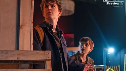 New look at Walker Scobell and Levi Chrisopulos in ‘PERCY JACKSON AND THE OLYMPIANS’ Season 3.  An official promotional still from the third season of the television series Percy Jackson and the Olympians. On the left, Percy Jackson, portrayed by a teenage Walker Scobell with curly light brown hair, stands in profile looking upward with a serious, alert expression. He wears a dark button-down shirt over a green top and a backpack. On the right, his younger half-brother Tyson, played by Levi Chrisopulos with short light brown hair and a wide-eyed, curious expression, looks up at Percy while standing close to him in a dimly lit indoor setting with exposed wooden beams and crates. An Entertainment Weekly logo reading "Fall Movie Preview 2026 Exclusive" is visible in the upper right corner.