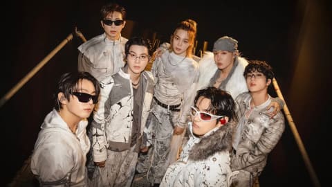 The global icons are pictured posing together behind the scenes at Estadio San Marcos. The K-pop supergroup BTS [Entity] is captured backstage during the South American leg of their highly anticipated global comeback series. Members RM, Jin, SUGA, j-hope, Jimin, V, and Jung Kook stand tightly grouped under dramatic backstage lighting, modeling an avant-garde ensemble of coordinated monochrome outfits. Their stage attire features intricate black-and-white splattered and distressed patterns, layered over textured white and cream fabrics, complemented by distinct dark sunglasses worn by several members.