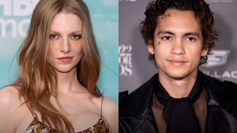 A side-by-side composite photo features two actors posing at red carpet events. On the left, a person with long, flowing strawberry blonde hair parted down the middle looks directly into the camera with a subtle expression, wearing a shimmering gold and brown sequined top against a teal background with white text. On the right, a person with short, curly dark brown hair and several small facial tattoos looks slightly off-camera with a gentle smile, dressed in a black leather jacket over a dark, sheer top with a tied neckline against a grey background featuring white logos.