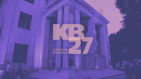 A large, grand building with towering stone pillars and wide concrete steps is bathed in a dramatic purple hue, serving as a backdrop for the Karachi Biennale. The architecture features tall rectangular windows and an expansive portico, with banners displaying "BIENNALE" hanging vertically down the columns. In front of the structure, a few individuals are scattered near the steps and base, appearing small against the monumental scale of the facade. Layered boldly over the center of the image is a large, stylized graphic text overlay reading "KB 27" and "KARACHI BIENNALE", accompanied by event dates indicating October 22 to November 5, '17, from 10 AM to 6 PM.