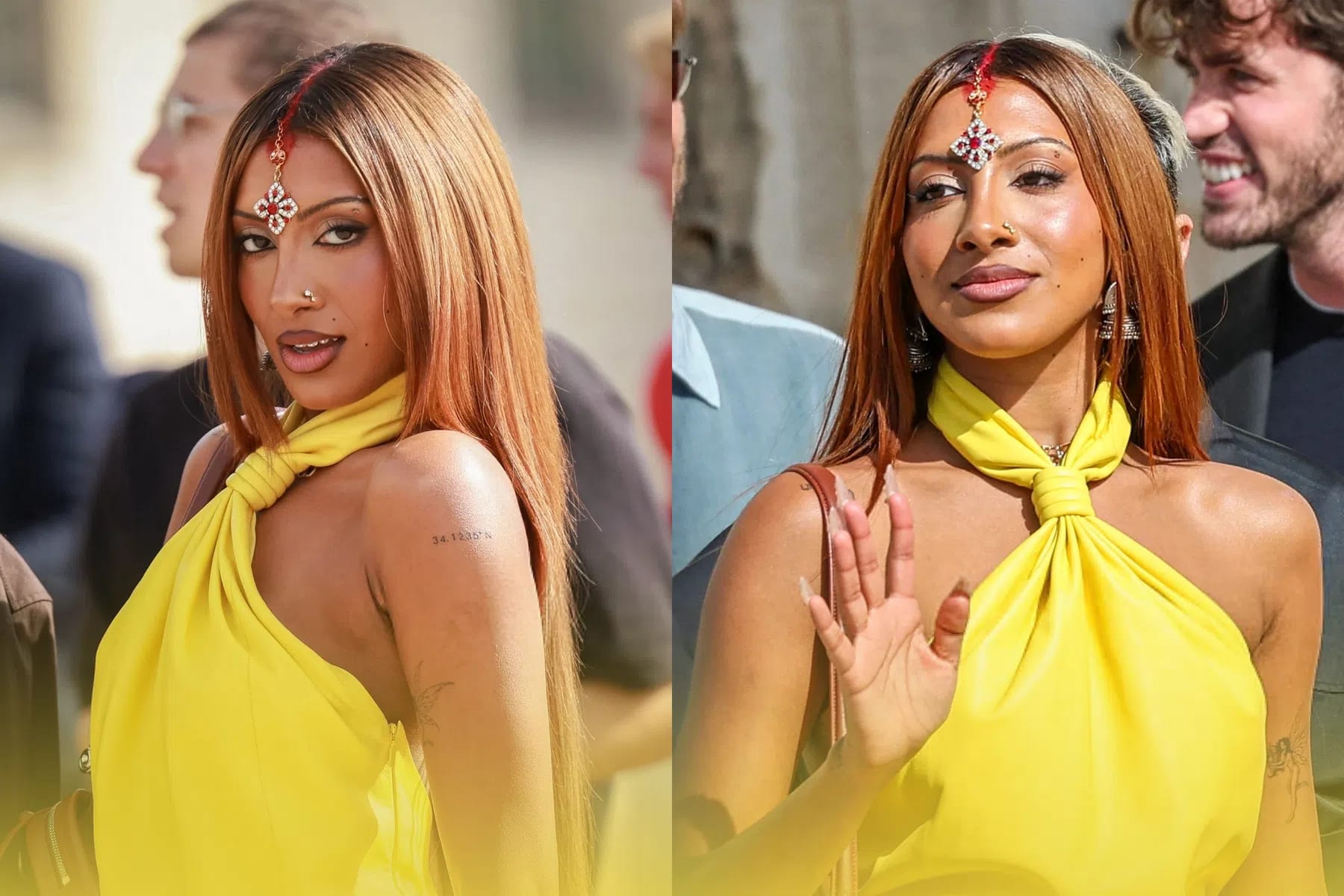 A side-by-side composite photo shows Lara Raj of the girl group KATSEYE outdoors, looking toward the camera. In both frames, she has long, straight, copper-brown hair parted down the middle, featuring a streak of red color along the part line and a decorative jeweled maang tikka forehead ornament. She is wearing a vibrant yellow halter-neck top or dress that twists at the front of the neck. In the left frame, she casts a sharp glance over her shoulder, showing a small text tattoo on her upper arm, while in the right frame, she waves one hand with neutral makeup and a nose ring visible.