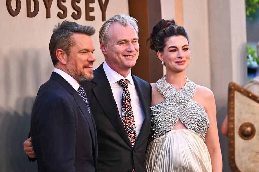 Matt Damon, director Christopher Nolan, and Anne Hathaway command the red carpet at the star-studded world premiere of The Odyssey on Tuesday, July 14, 2026, at the AMC Lincoln Square theater in New York City. Standing together from left to right, the powerhouse trio celebrates the release of their highly anticipated epic fantasy blockbuster, marking a major cinematic reunion over a decade after they first collaborated on 2014's Interstellar. Positioned in the center, Nolan guides his leading actors through a wave of flashing cameras and cheering fans, just days ahead of the film's global theatrical rollout. The high-profile event draws massive media attention to Manhattan's Upper West Side, anchoring the promotional tour for a film that has already made headlines as the first feature shot entirely on IMAX 70mm cameras.