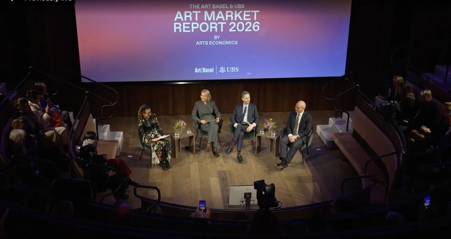 This image depicts a live panel discussion for the launch of The Art Basel & UBS Art Market Report 2026, authored by Dr. Clare McAndrew of Arts Economics. Moderated by Melanie Gerlis (Financial Times), the panel features Noah Horowitz (CEO of Art Basel), Paul Donovan (Chief Economist of UBS Global Wealth Management), and Dr. Clare McAndrew seated on a stage inside a modern lecture hall. Behind them, a large screen displays the report's title against a gradient purple and blue background. The event, which took place at the Royal Academy of Arts in London, focuses on the recalibration of the global art market following a period of modest growth in 2025. 